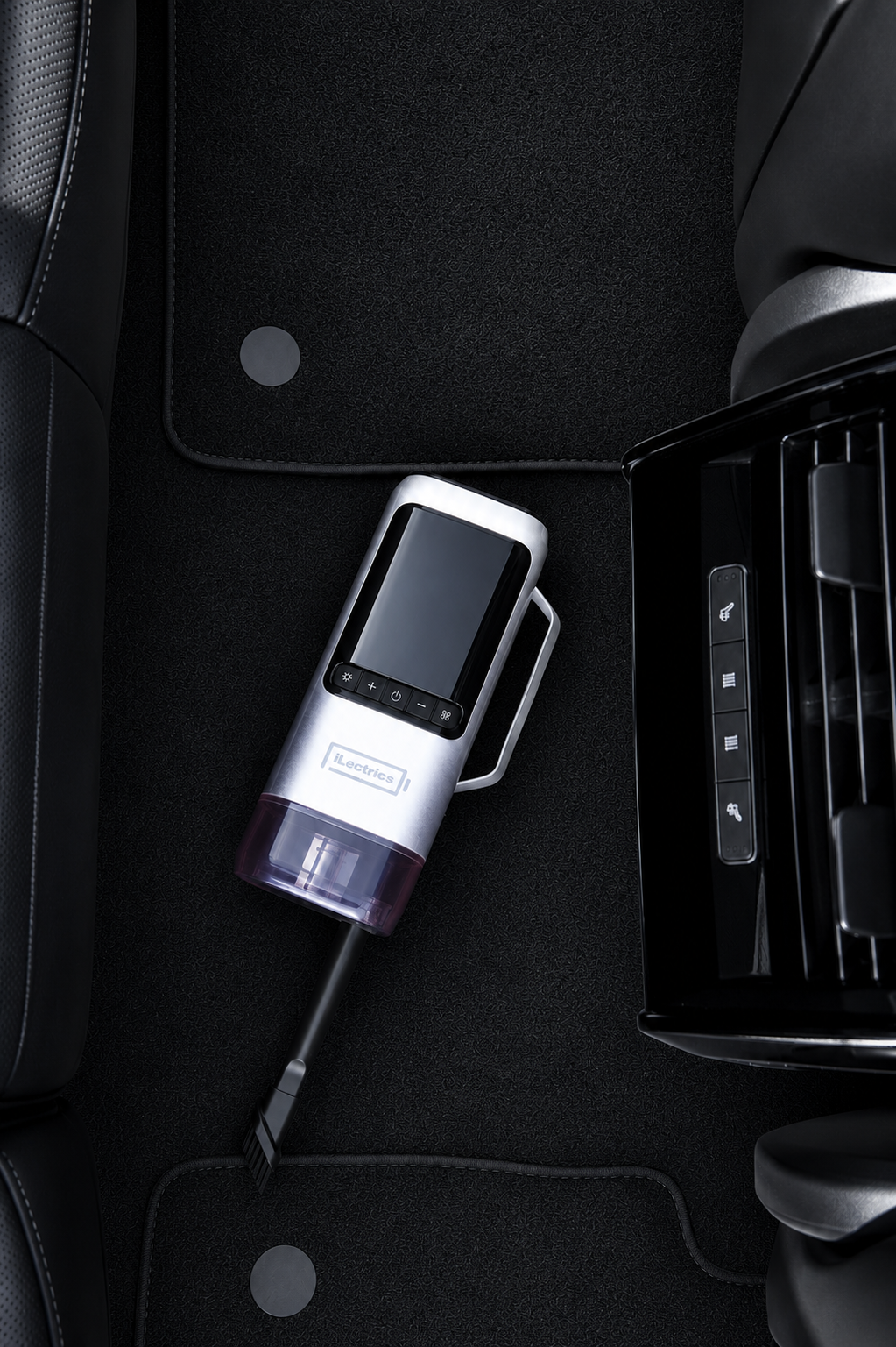 A handheld car vacuum cleaner with a screen, shown placed on a black car floor mat next to the center console.